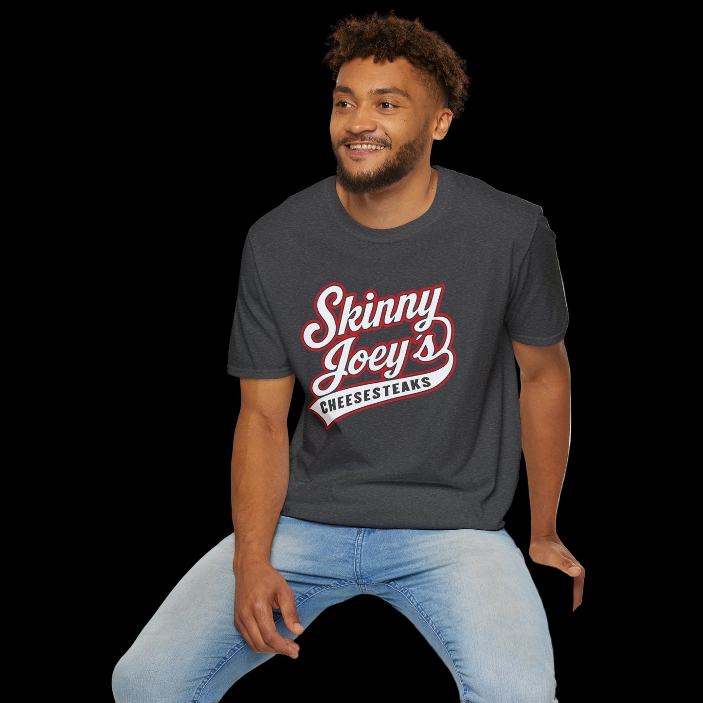 Man wearing a dark gray t-shirt with 'Skinny Joey's Cheesesteaks' text, sitting on a white stool against a white background.