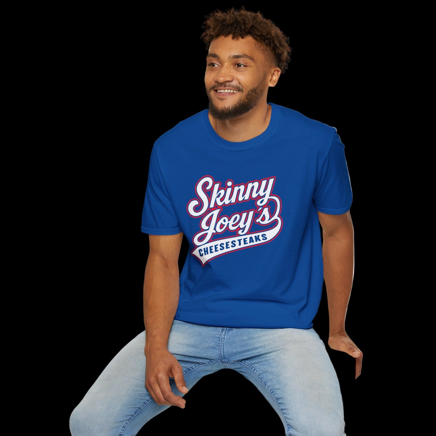 Man wearing a blue t-shirt with 'Skinny Joey's Cheesesteaks' text, sitting on a white stool against a white background.