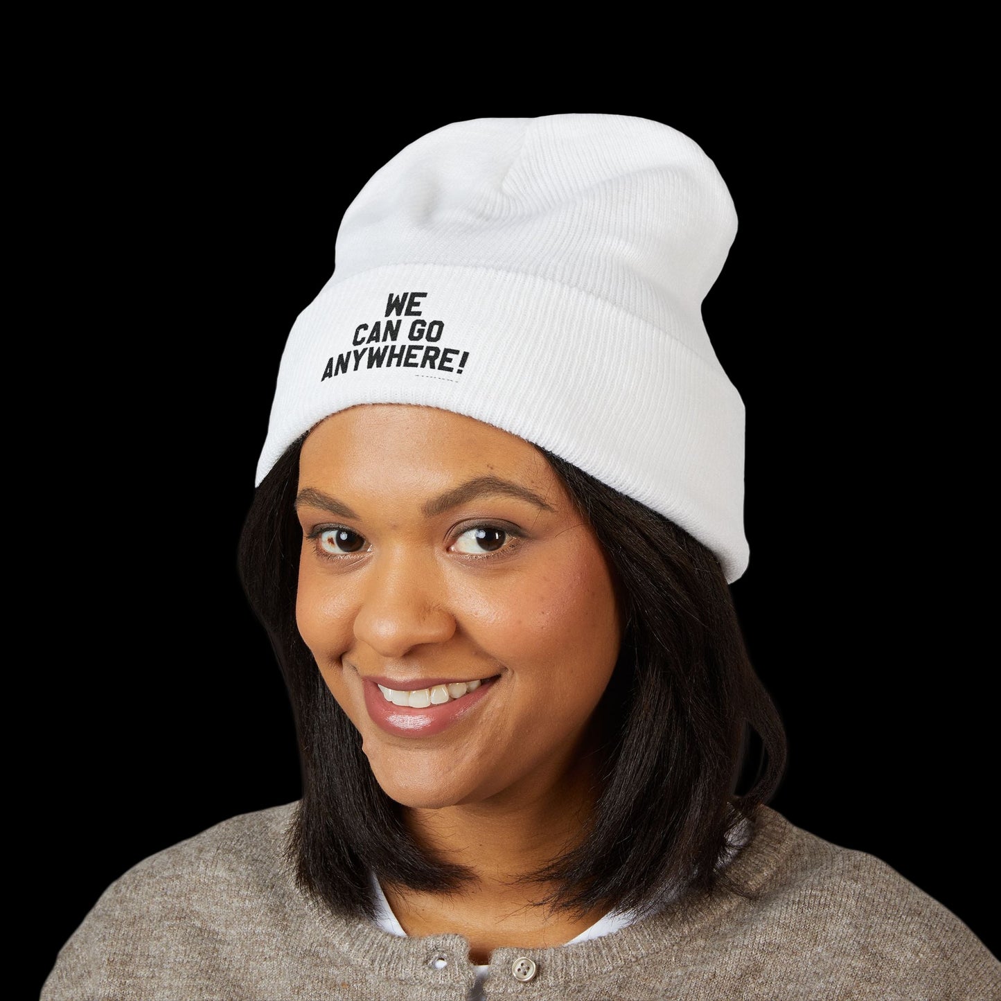 Person wearing a white beanie with 'WE CAN GO ANYWHERE!' text on a black background