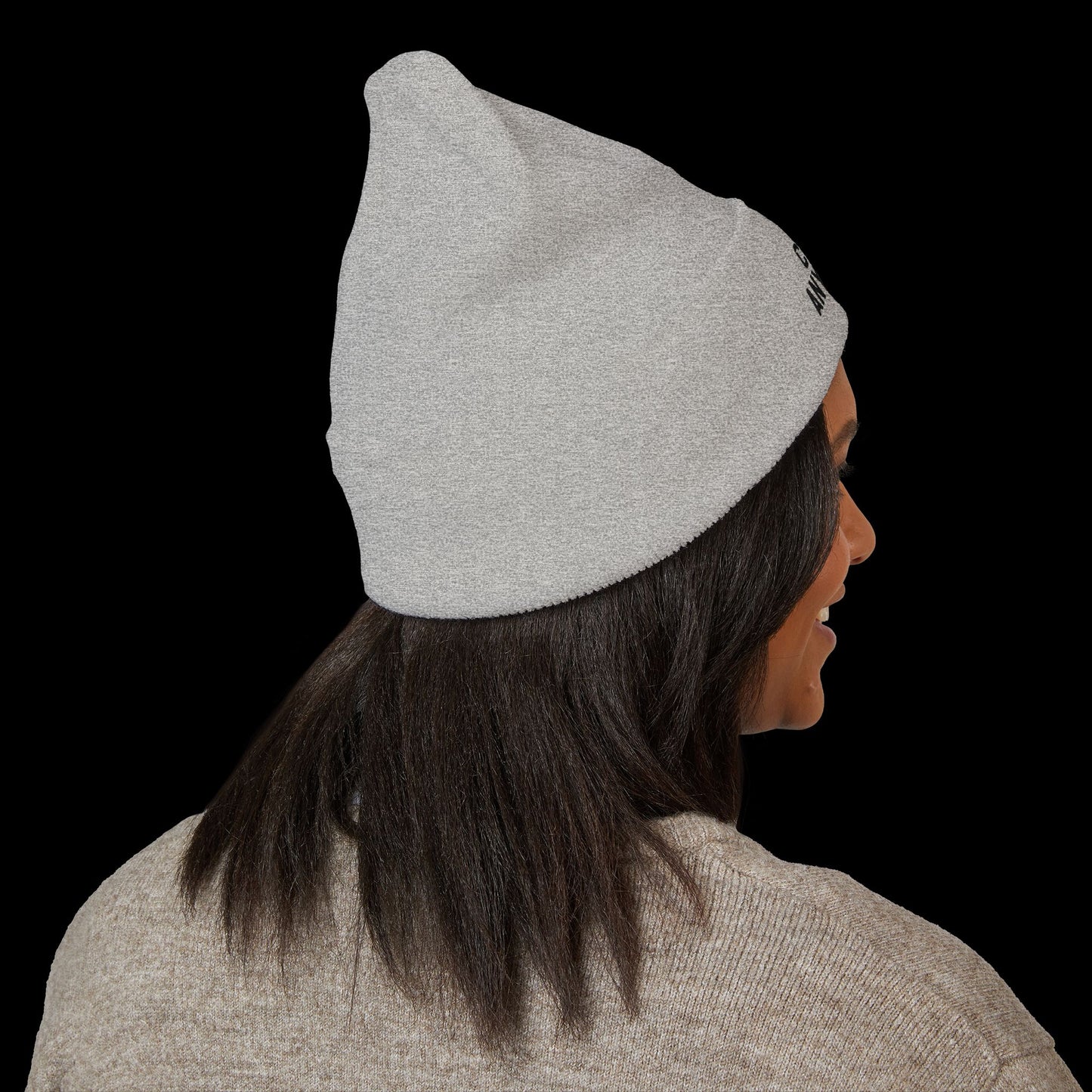Person wearing a gray beanie with a logo on a black background