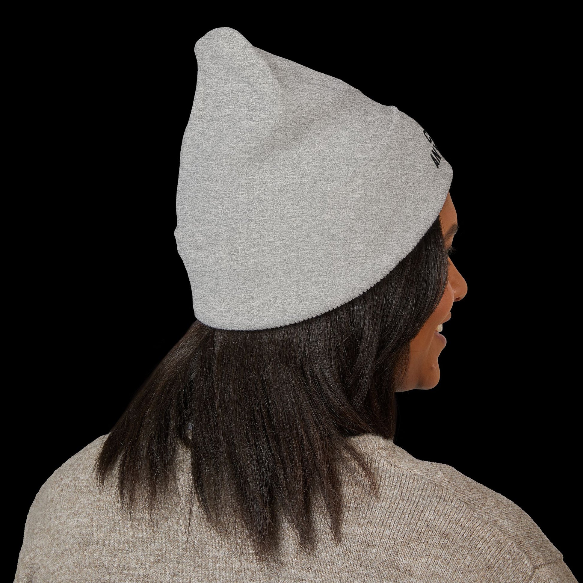 Person wearing a gray beanie with a logo on a black background