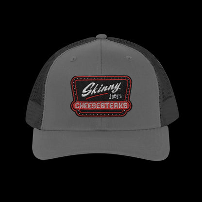 Gray and black trucker hat with 'Skinny Joey's Cheesesteaks' logo on a white background