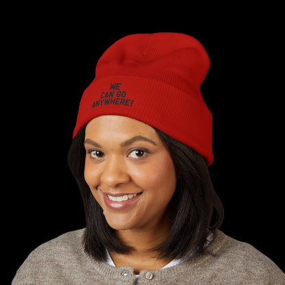 Person wearing a red beanie with text, smiling against a black background