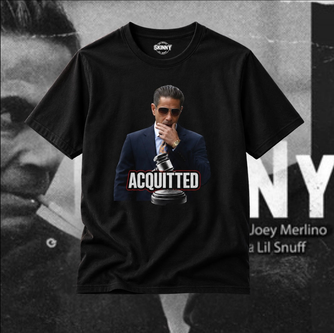 A black short-sleeve graphic t-shirt featuring a printed image of Joey Merlino in a suit and sunglasses with the word 'ACQUITTED' and a gavel. The shirt is displayed against a black-and-white background with text reading 'JOEY MERLINO' and 'Lil Snuff'.