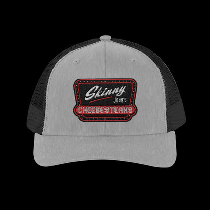 Gray and black trucker cap with 'Skinny Joey's Cheesesteaks' logo on a white background