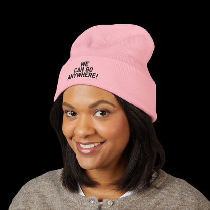 Person wearing a pink beanie with 'WE CAN GO ANYWHERE!' text on a black background