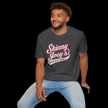 Man wearing a dark gray t-shirt with 'Skinny Joey's Cheesesteaks' text, sitting on a white stool against a white background.