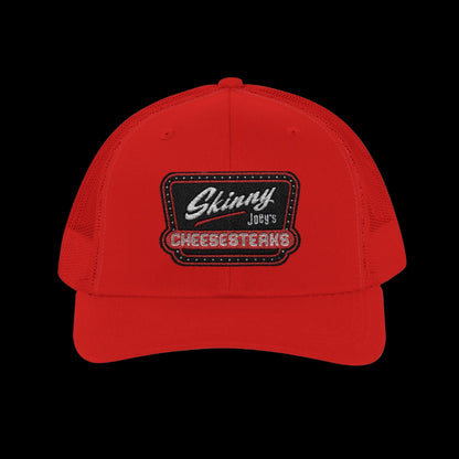 Red cap with 'Skinny Joey's Cheesesteaks' logo on a white background