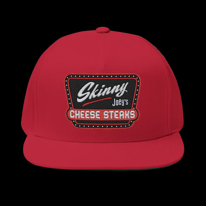 Red cap with 'Skinny Joey's Cheese Steaks' logo on a white background