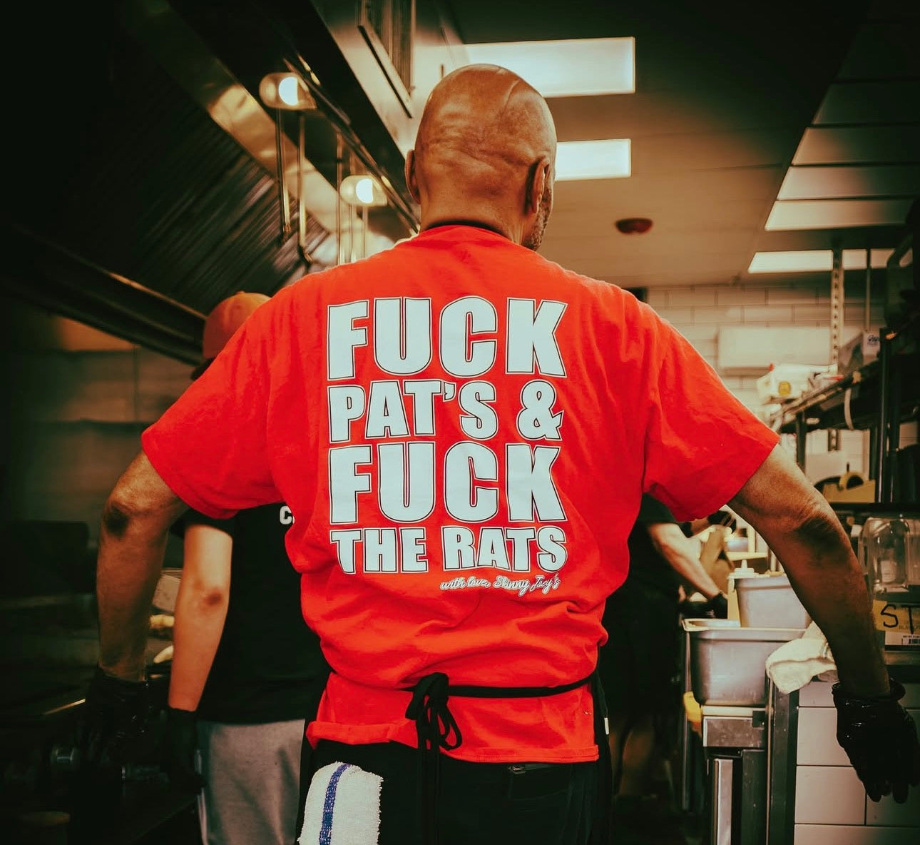 Person wearing a red shirt with offensive text in a kitchen setting