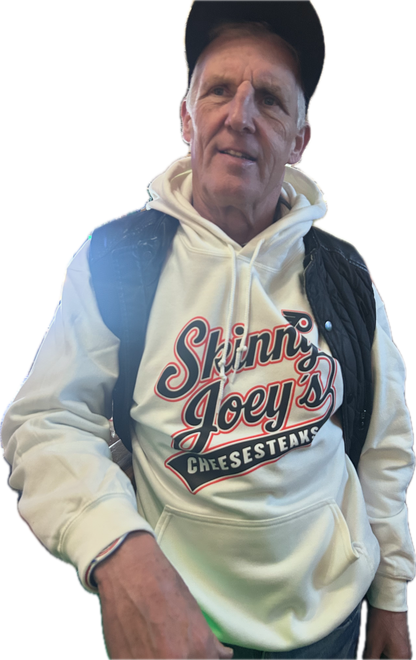Man wearing a white hoodie with 'Skinny Joey's Cheesesteaks' text and graphics.