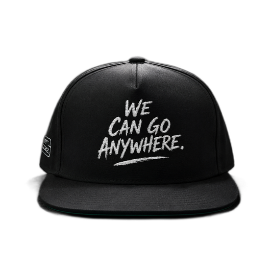 A black flat-brim snapback cap with white embroidered text reading 'WE CAN GO ANYWHERE.' on the front, shown against a plain white background.