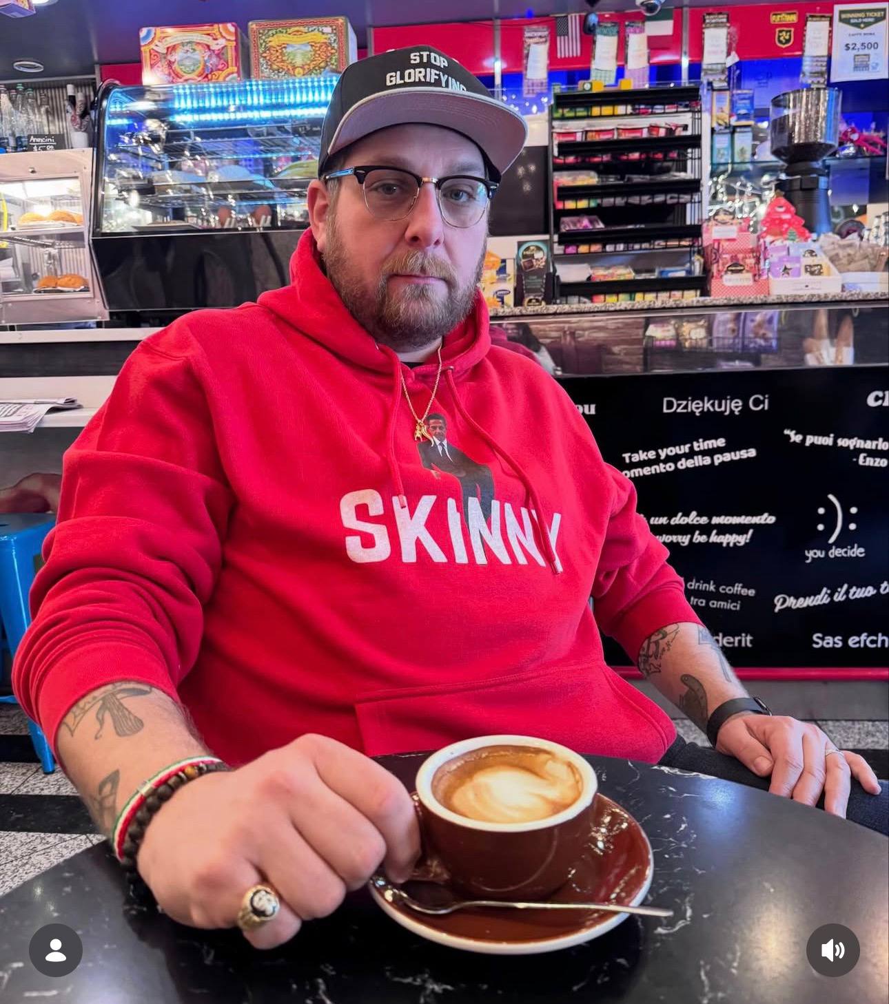 Red hoodie with a graphic of a person in a suit and the word 'SKINNY' on a black background